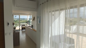 A spacious balcony with a view of the countryside, a modern kitchen area, and a living space with a large window covered by sheer curtains. - 3 Bedroom villa with swimming pool in quiet village with countryside views (Alcobaca)