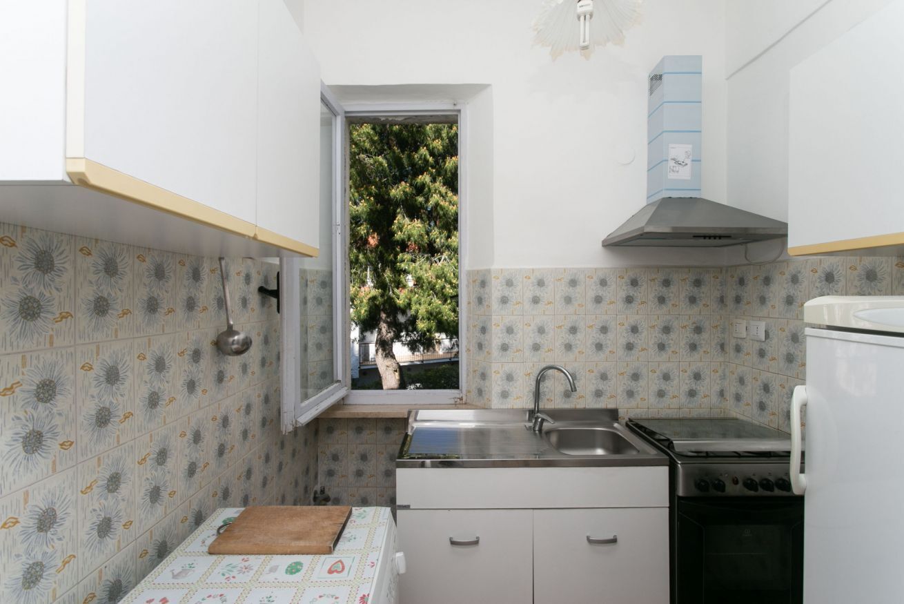 Una cucina compatta con finestra, lavello, fornello e frigorifero.
