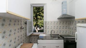 Una cucina compatta con finestra, lavello, fornello e frigorifero.