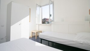 Een slaapkamer met een bed, een klein tafeltje, een kledingkast en een raam met uitzicht.