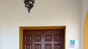 Une porte double marron ornée de motifs décoratifs, une enseigne au-dessus, et un mur recouvert de carreaux avec une bordure jaune et verte.