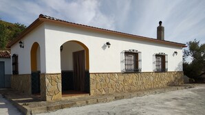 Un bâtiment à deux étages, avec une base en pierre et des murs blancs, doté d’un toit en tuiles, de portes en arc de cercle et d’une cheminée.
