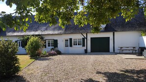 En hvid bygning med grusvej, grøn dør og sort garagedør.