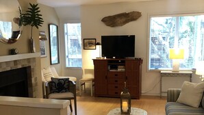 Ein Wohnzimmer mit Kamin, Fernseher, Sofa und Couchtisch.