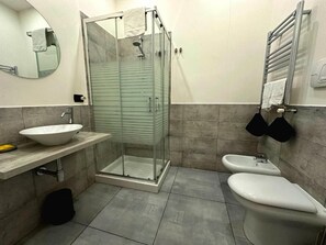 A modern bathroom with a glass-enclosed shower, a white sink, and a toilet.