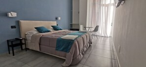 A bedroom with a bed, bedside tables, a chair, and a window with curtains. - Hi Relais Rooms (Naples)