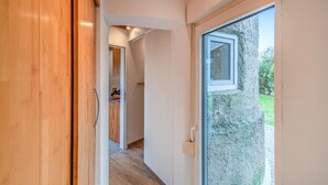 A hallway with a wooden door, a glass door leading outside, and a view of a garden. - Gorgeous home in Otterndorf with WiFi (Otterndorf)
