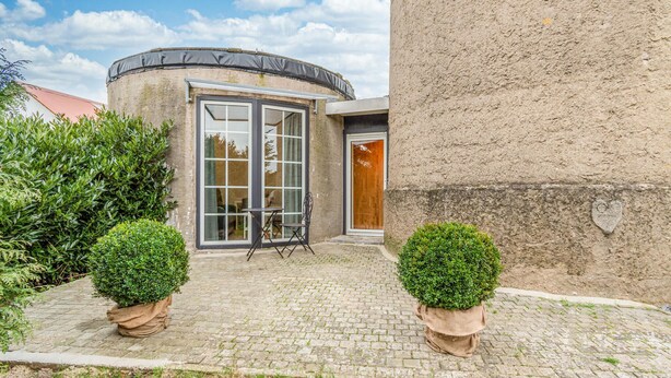 A building with a circular window, a door with a wooden panel, and two potted plants. - Gorgeous home in Otterndorf with WiFi (Otterndorf)
