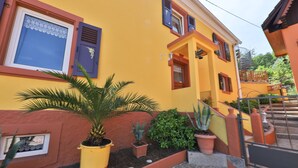A yellow building with a red door, windows with blue shutters, and a staircase leading to a balcony. - Maison Balboa gîtes for 2 to 12 people (Sondernach)