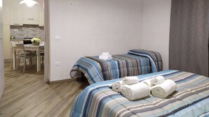 Habitación de hotel con dos camas, una zona de comedor y una kitchenette.