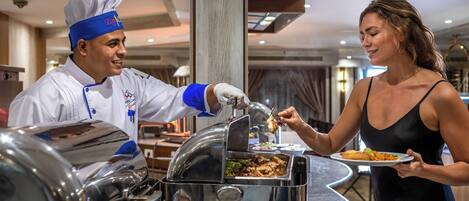 Een buffetopstelling, waarbij een kok eten serveert aan een gast.