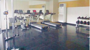 Un gimnasio con cintas de correr, máquinas de pesas y mancuernas.