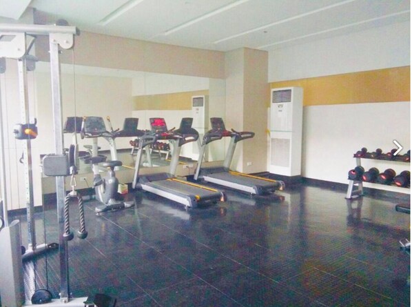 A gym with treadmills, weight machines, and dumbbells.