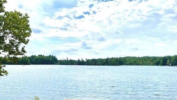 Kaunis paikka järven rannalla, jossa on sinisiä tuoleja ja puinen laituri, joka ulottuu veteen.