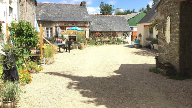 A courtyard with stone buildings, a gravel path, and outdoor seating. - Webb's of Glomel (Glomel)