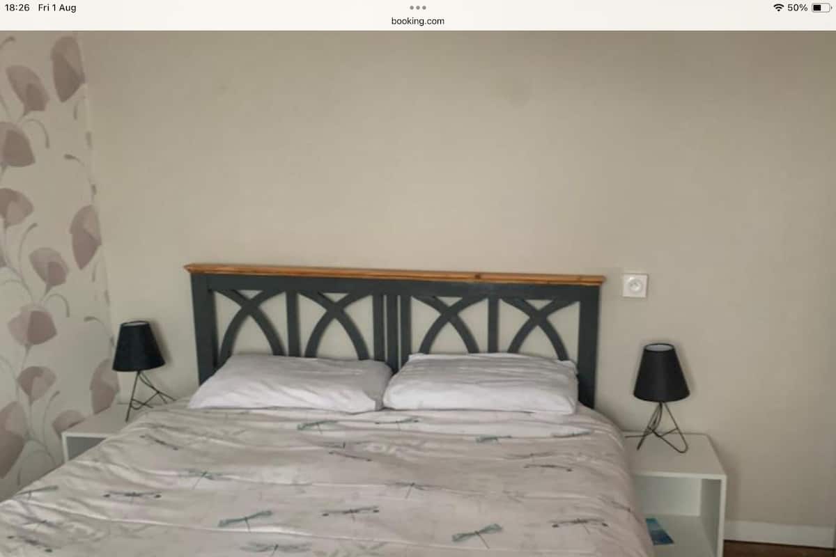 A bedroom with a bed, two bedside tables, and a wall with a leaf pattern.
