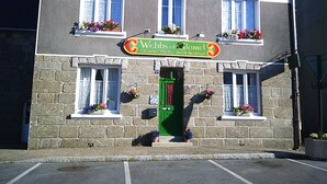 A two-story building with a green door, multiple windows, and flower boxes on the upper floor. - Webb's of Glomel (Glomel)