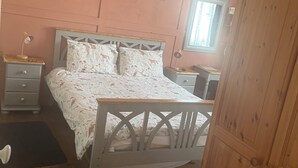 A bedroom with a bed, bedside tables, a wardrobe, and a window. - Webb's of Glomel (Glomel)
