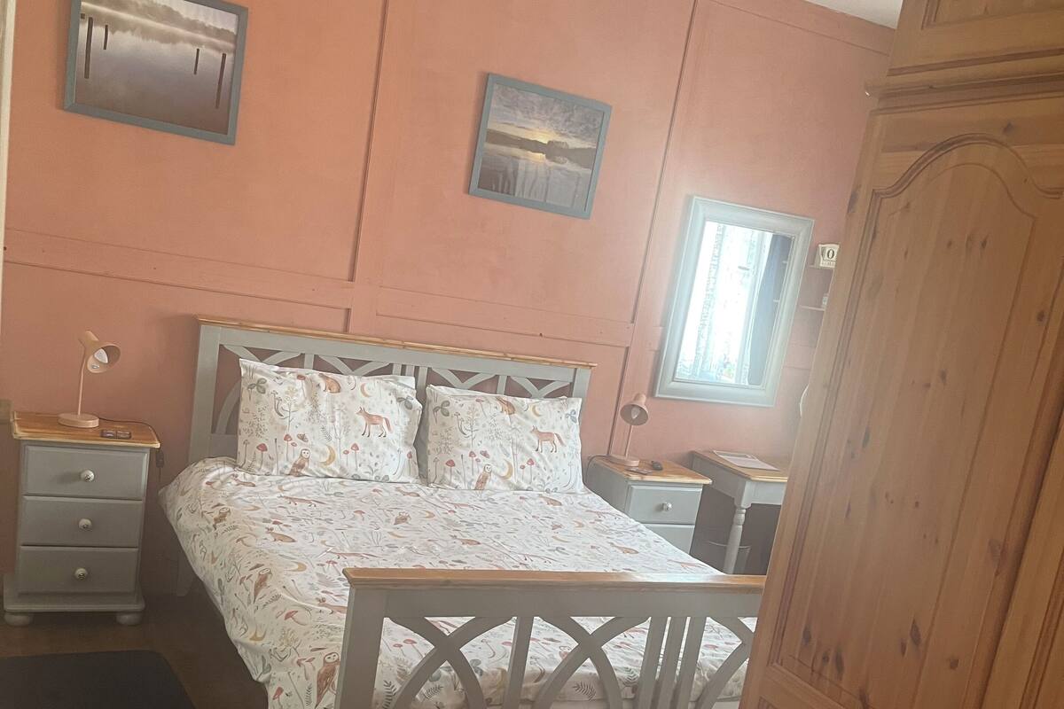 A bedroom with a bed, bedside tables, a wardrobe, and a window.