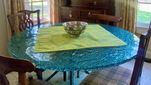 A dining area with a round glass table, chairs, and a wooden cabinet.