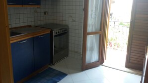 Una cocina compacta con gabinetes azules, una estufa y un lavamanos.