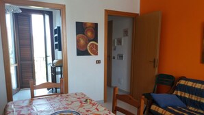 Una habitación con una mesa de comedor, sillas, un sofá y una puerta que da a un balcón.