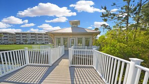 A wooden deck with white railings leading to a building with a gabled roof and large windows. - *30A Seagrove Highlands Ground Floor Unit- 2 bikes included (Santa Rosa Beach)