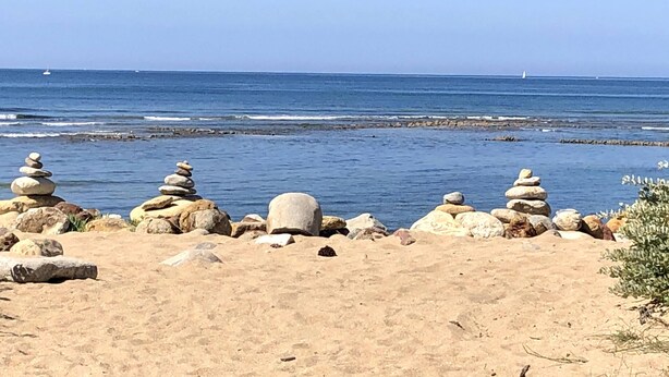 Una playa con montones de piedras y una vista despejada del océano.