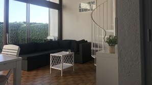 Una sala de estar moderna con un sofá negro, una mesa de centro blanca y una escalera en espiral.