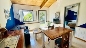 Un salon chaleureux avec un plafond en bois, une table à manger, un canapé et un téléviseur.