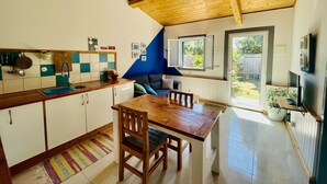 Une cuisine avec des meubles de rangement en bois, un évier et un coin repas comprenant une table et des chaises.