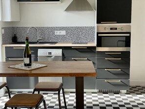 A modern kitchen with a checkered floor, a wooden table, and a wine bottle.