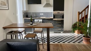 A modern kitchen with a checkered floor, a dining table, and a bottle of wine.