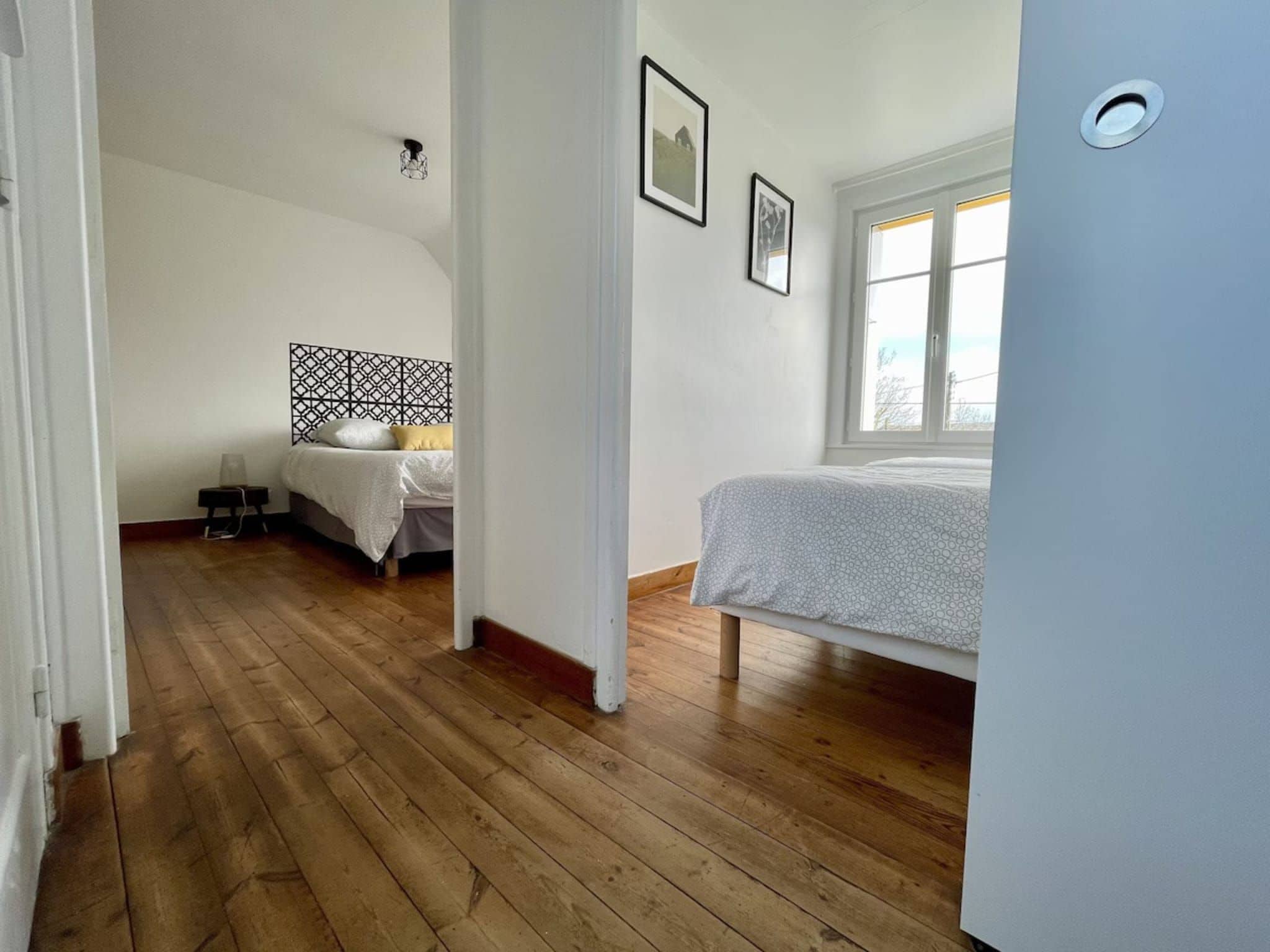 Ein Schlafzimmer mit Holzboden, einem Bett mit gemustertem Überwurf, einem Nachttisch und einem Fenster mit Aussicht.