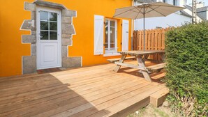 A wooden deck with a picnic table and umbrella, a white door, and a wooden fence.