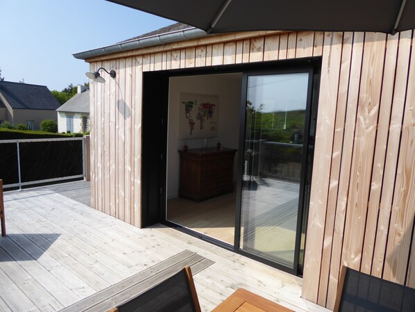 A wooden deck with a sliding glass door leading to an interior space with a wooden cabinet and a map on the wall.
