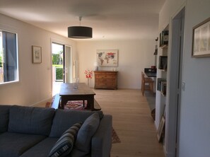 A modern living room with a sofa, a dining table, and a kitchen area with a map on the wall.
