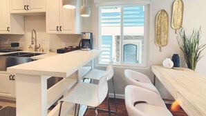 Een moderne keuken met witte kasten, een centraal eiland en barstoelen.