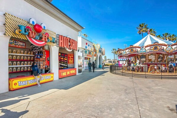 A street with a Clown Rounds store, a hot shot sign, and a carousel.