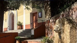 A courtyard with a fountain, steps leading to a door, and a stone wall.