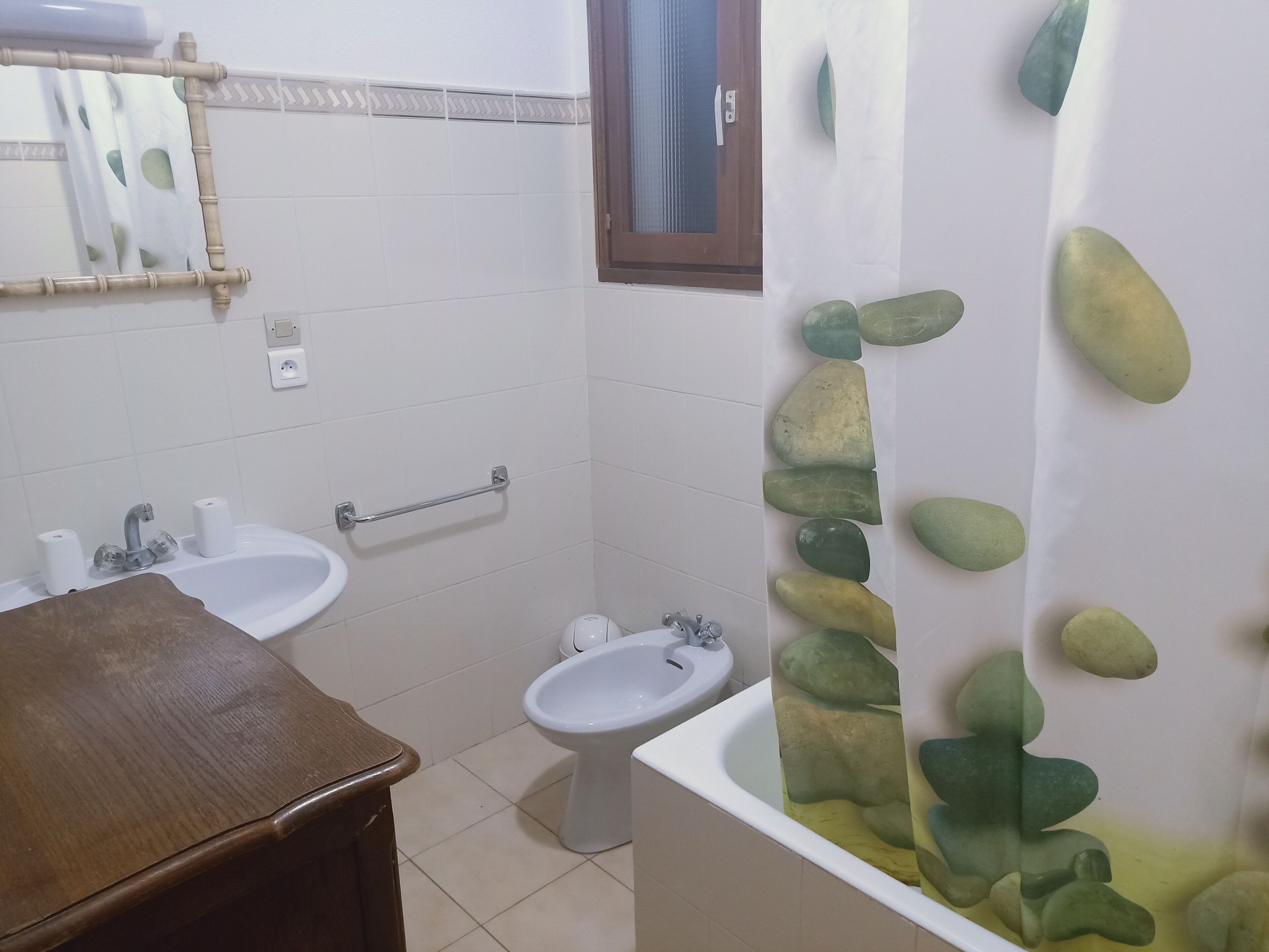 Ein Badezimmer mit zwei Waschbecken, einer Toilette und einer Badewanne mit Steinwand-Design.