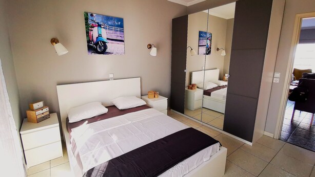 Een slaapkamer met een bed, nachtkastjes, een spiegel en kunst aan de muur.
