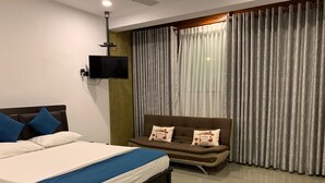 A modern hotel room with a bed, a sofa, a flat-screen TV, and a large window with curtains. - villacork face the river (Galle)