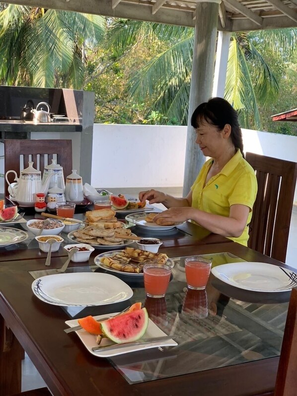 Una mesa de comedor con diversos platos, incluyendo rebanadas de sandía, y una persona sentada.