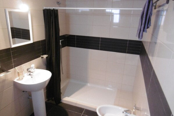 A bathroom with a white sink, a bathtub, and a shower area.