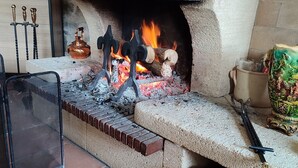 A fireplace with burning logs, a metal screen, and a brick structure. - The charm of the Breton countryside (Quemper Guezennec)