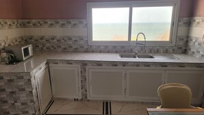A kitchen with a view of the sea, a sink, and cabinets. - Chez Medzo (Toubab Dialao)