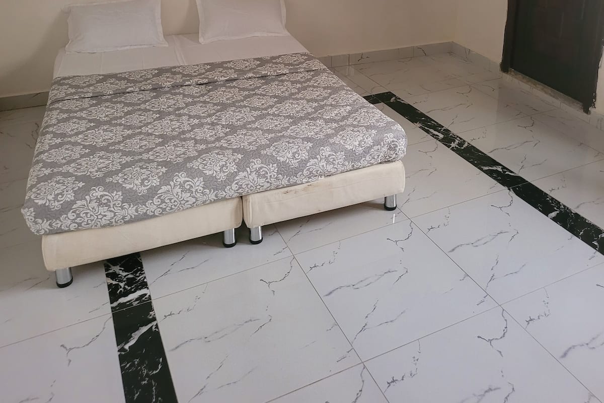 A room with a bed, a door, and a tiled floor.