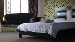 Una habitación de hotel con cama, sofá y ventana con cortinas.