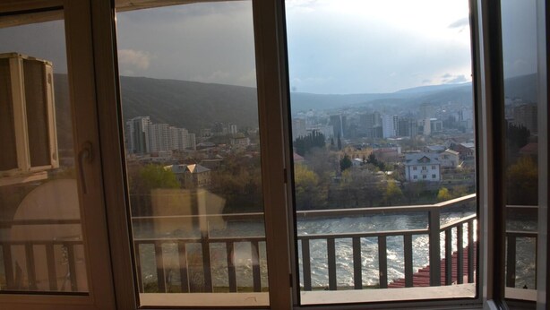 Una habitación con un ventanal grande que da a un paisaje urbano y un río.